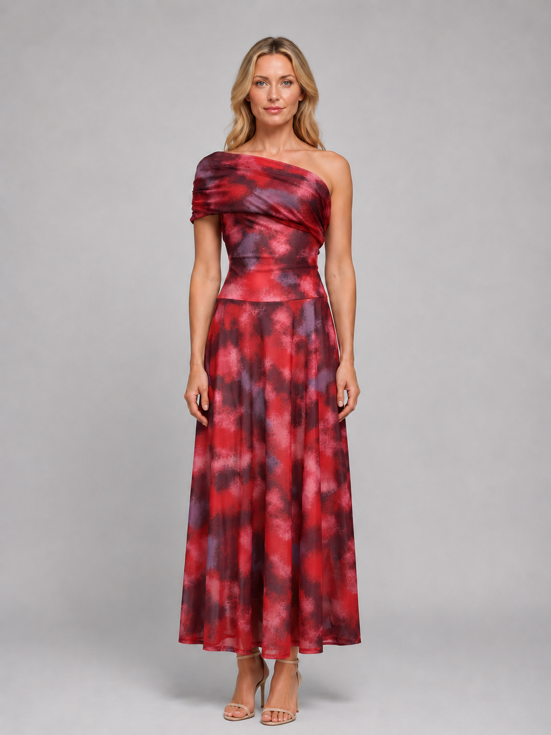 Woman wearing red and purple tie-dye one-shoulder maxi dress with flowing skirt and metallic sandals