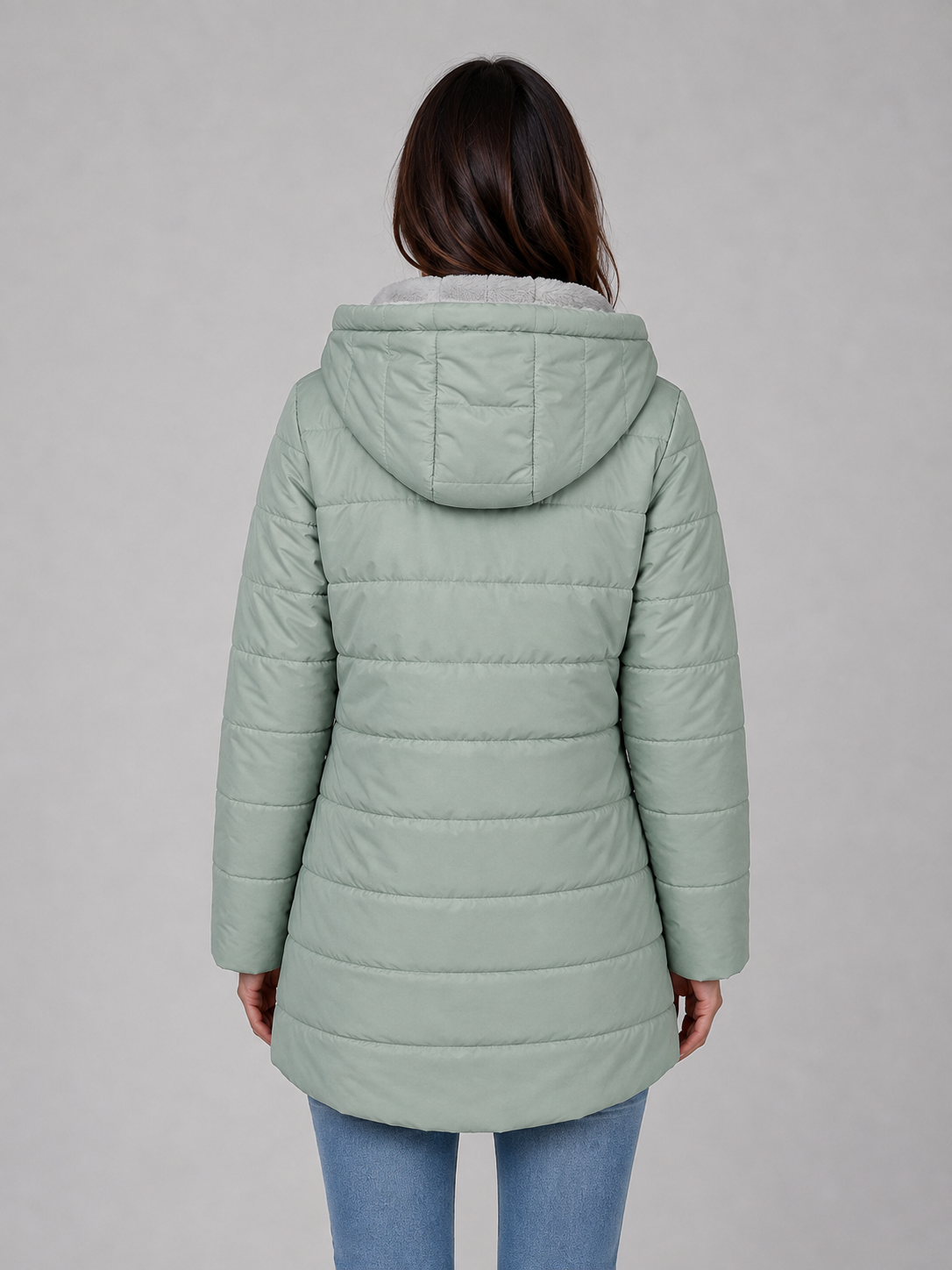 Woman wearing sage green quilted puffer jacket with hood and fleece lining, paired with blue jeans, shown from back view
