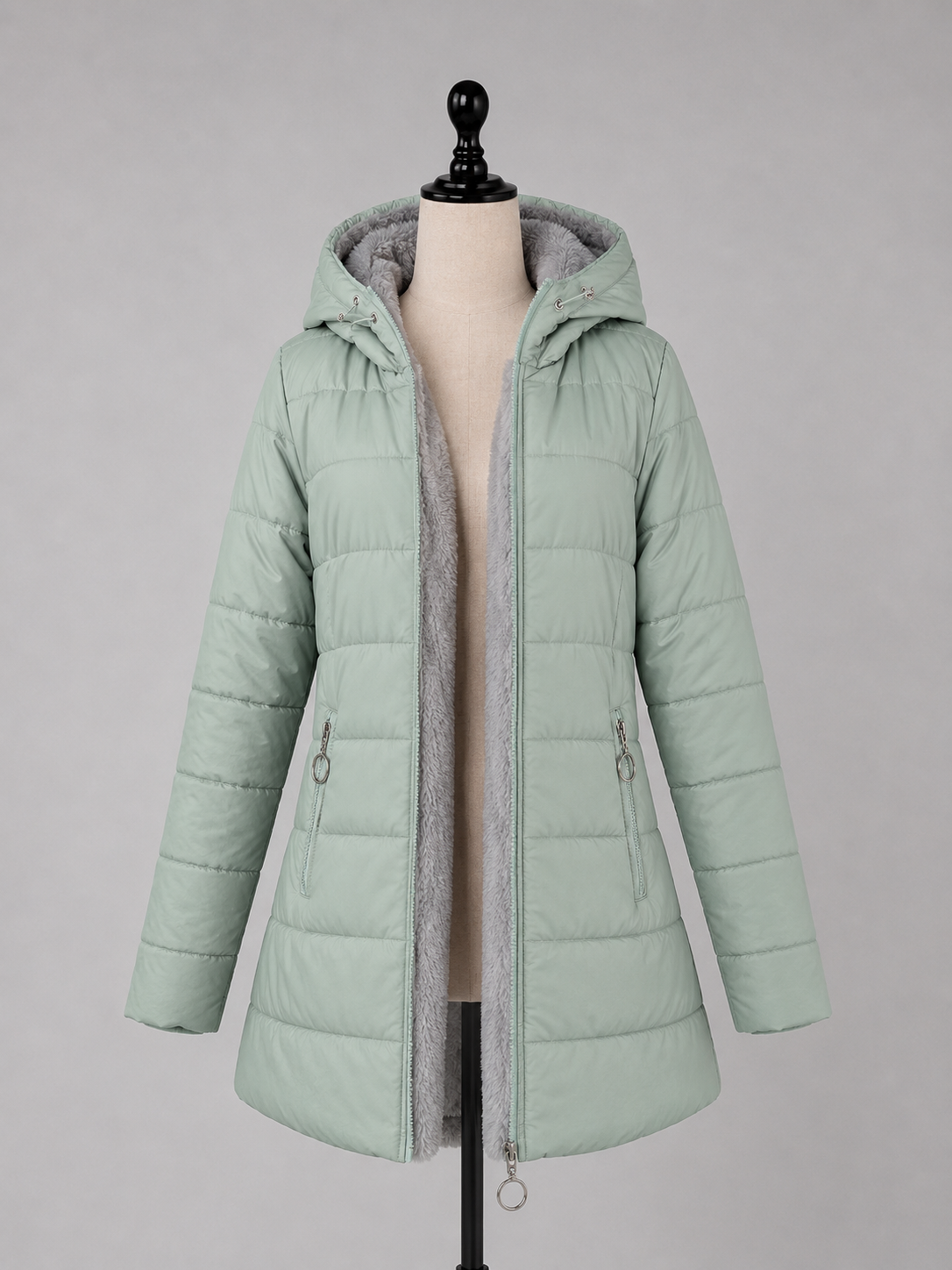 Women's mint green quilted puffer jacket with hood and gray fleece lining displayed on dress form