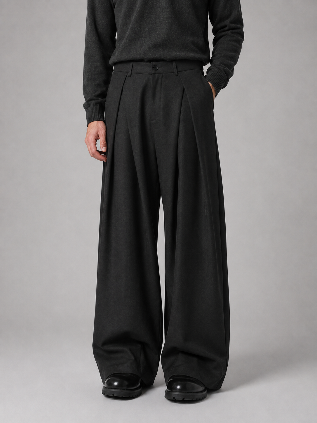 Man wearing black pleated wide leg tailored trousers with dark sweater and black chunky shoes