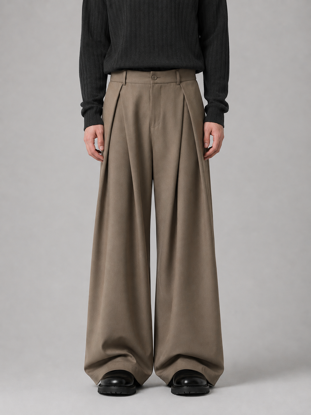 Men's pleated tailored baggy wide leg trousers in beige, styled with black ribbed sweater and black platform sandals