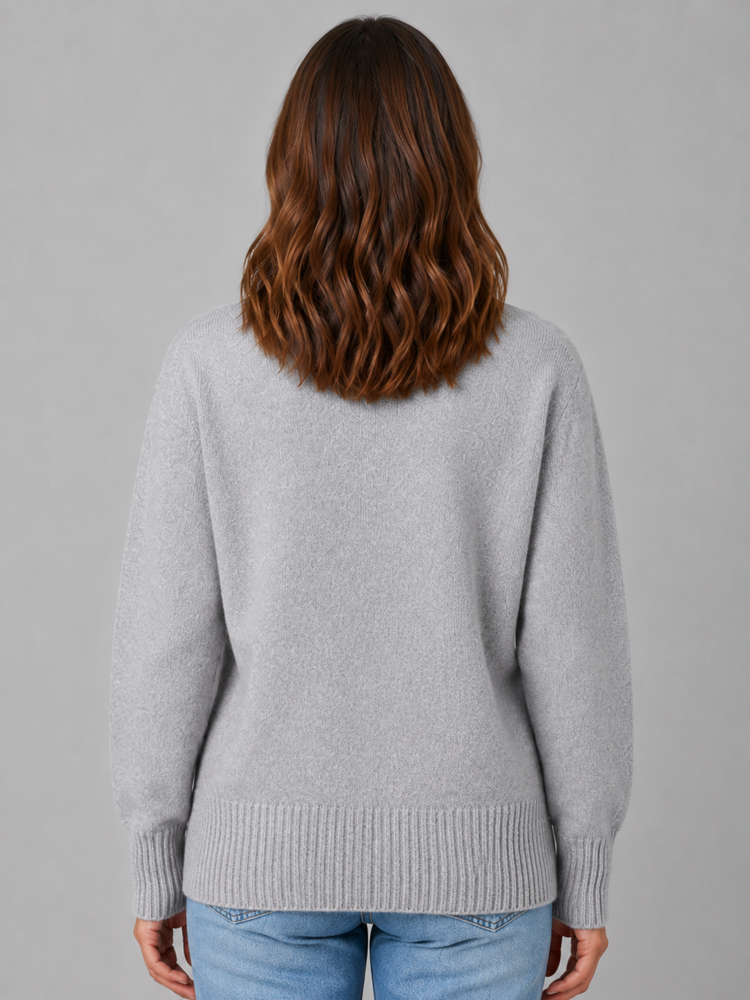 Woman wearing light gray soft knit v-neck cardigan with ribbed cuffs and hem, shown from back view