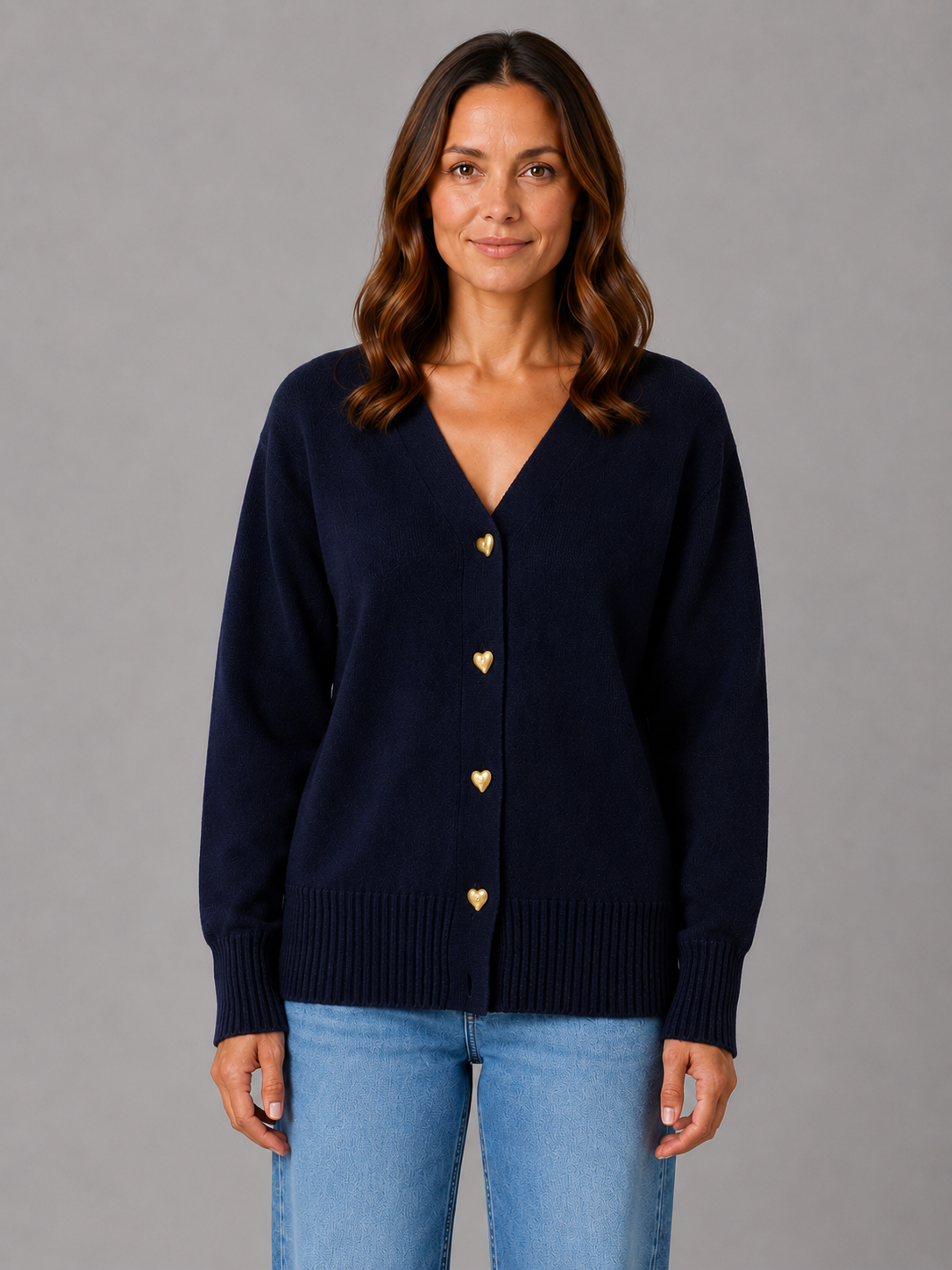 Woman wearing navy blue soft knit cardigan with heart-shaped buttons over light blue jeans