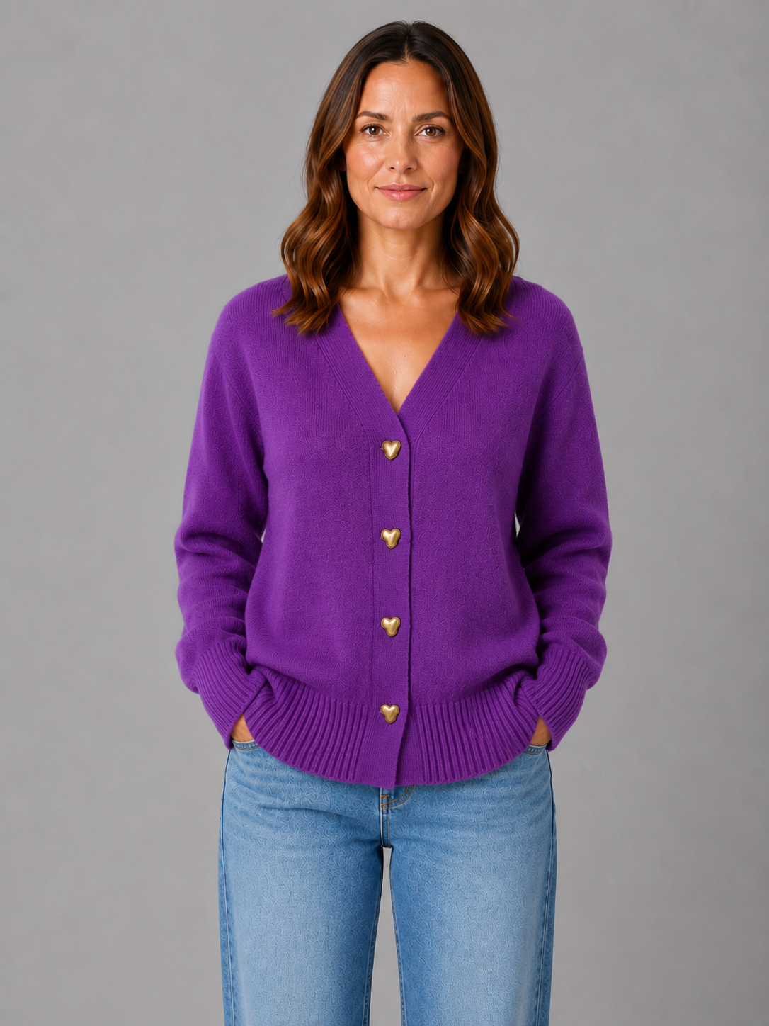 Woman wearing purple knit cardigan with heart-shaped buttons and v-neckline, paired with light blue jeans