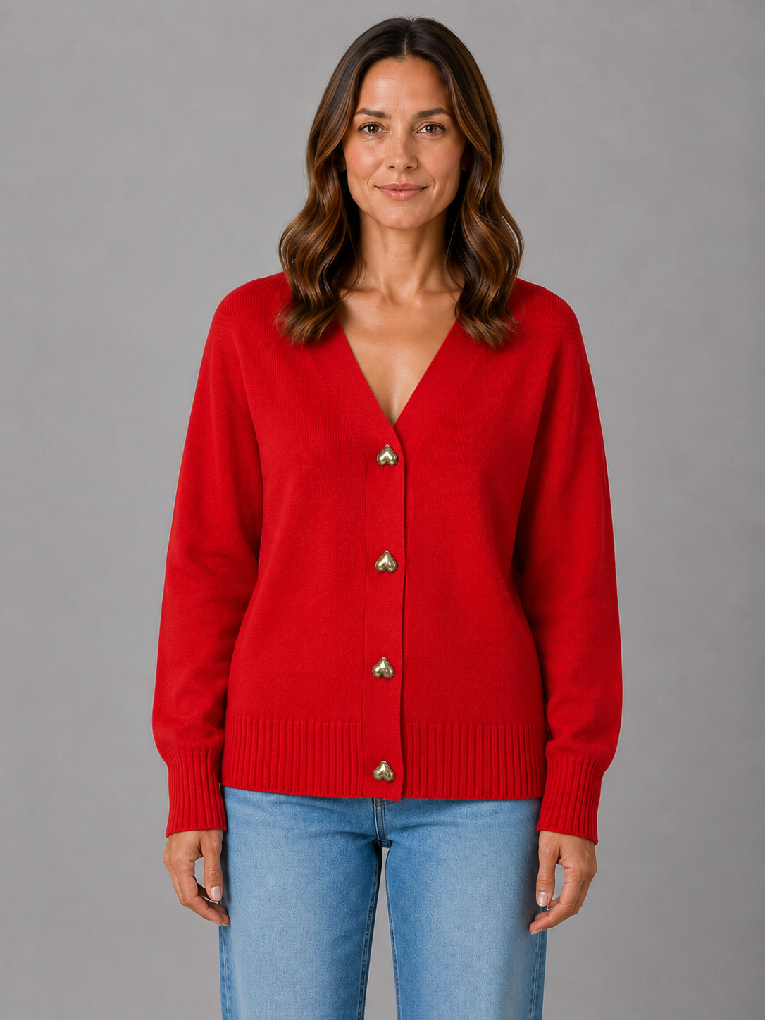 Woman wearing red soft knit cardigan with heart-shaped buttons and ribbed cuffs, styled with light blue jeans