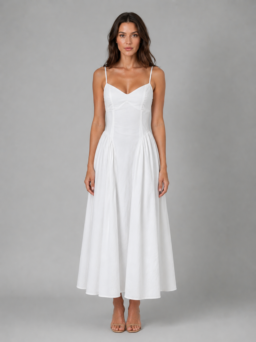 Woman wearing white sleeveless corset-style midi dress with full skirt and thin straps, paired with tan sandals