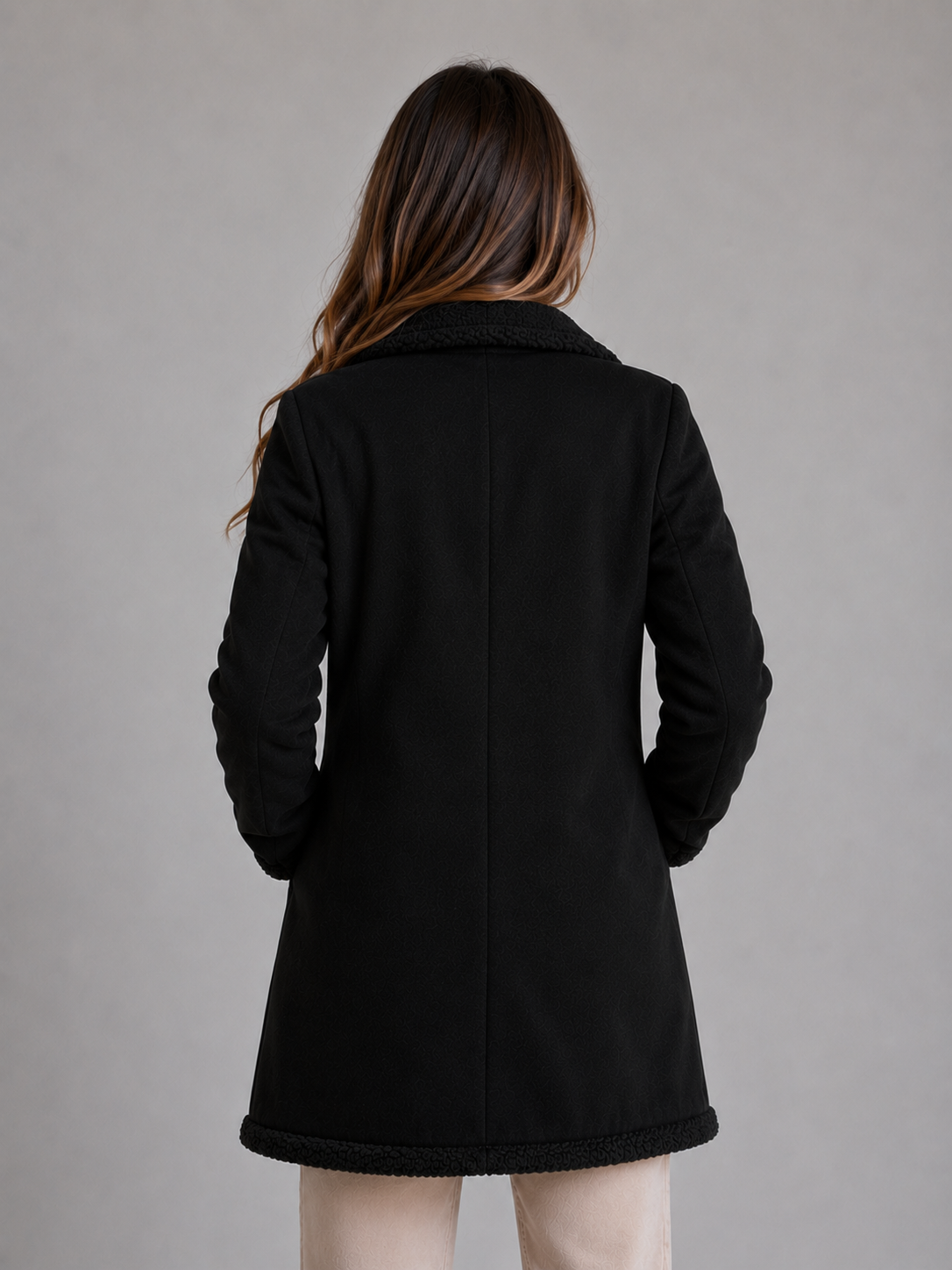 Woman wearing black longline shearling suede coat with teddy trim collar and hem, shown from back view
