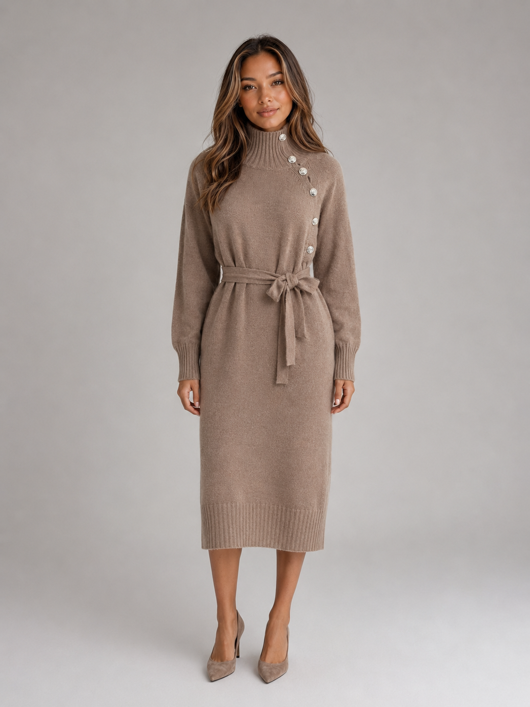 Woman wearing a beige roll neck cotton knit midi dress with buttons and tie belt, styled with nude heels