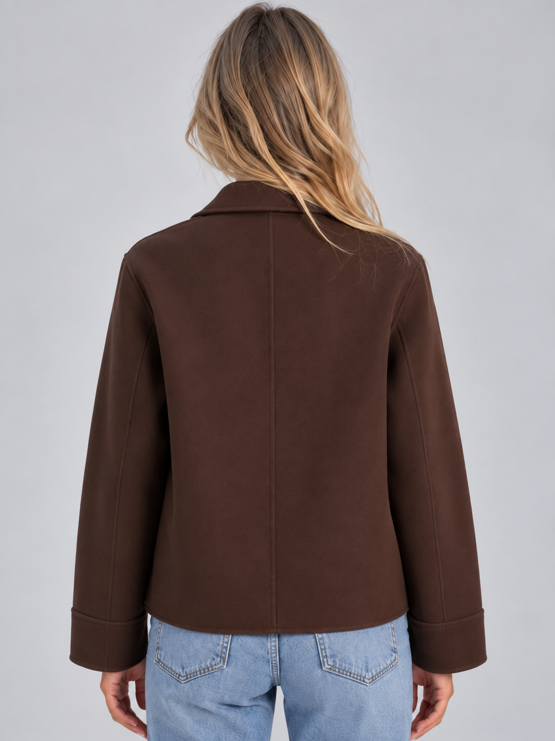 Woman wearing brown button-up collared overshirt jacket with patch pockets over light blue jeans, back view