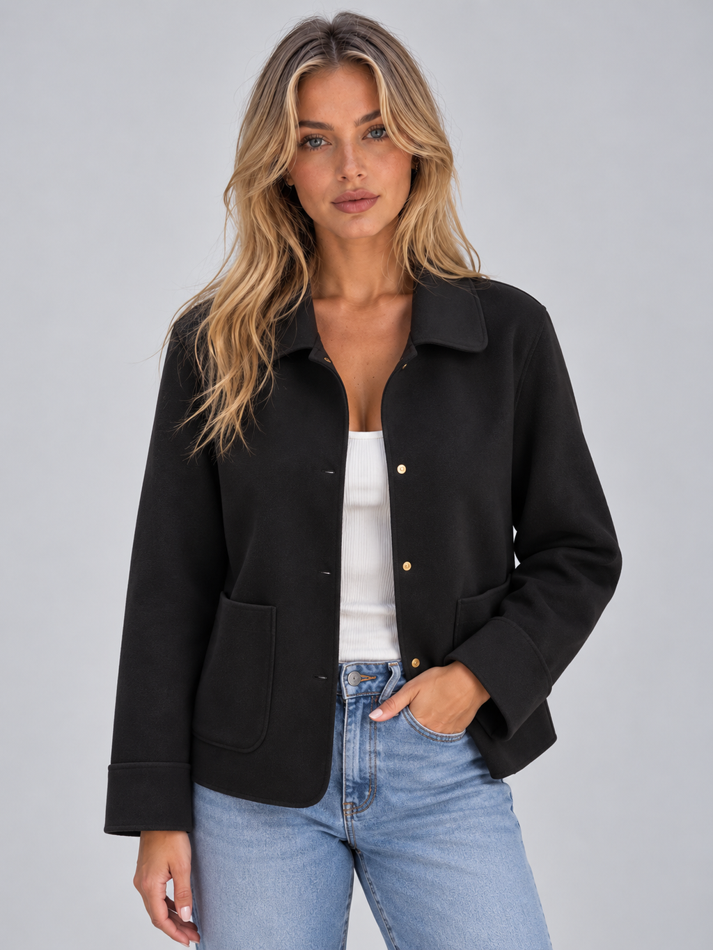 Woman wearing black button-up collared overshirt jacket with patch pockets over white ribbed top and blue jeans