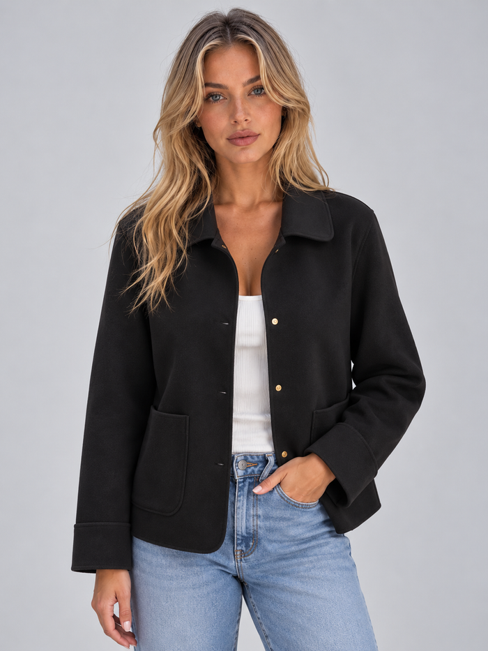 Woman wearing black button-up collared overshirt jacket with patch pockets over white ribbed top and blue jeans
