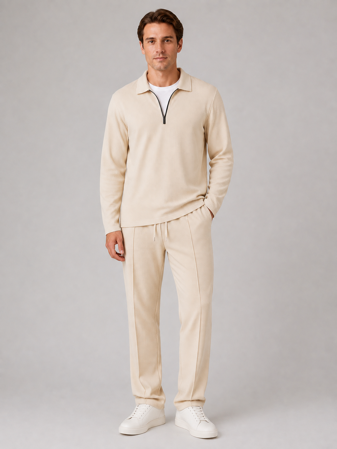 Man wearing cream textured quarter-zip polo shirt and matching trousers with white sneakers