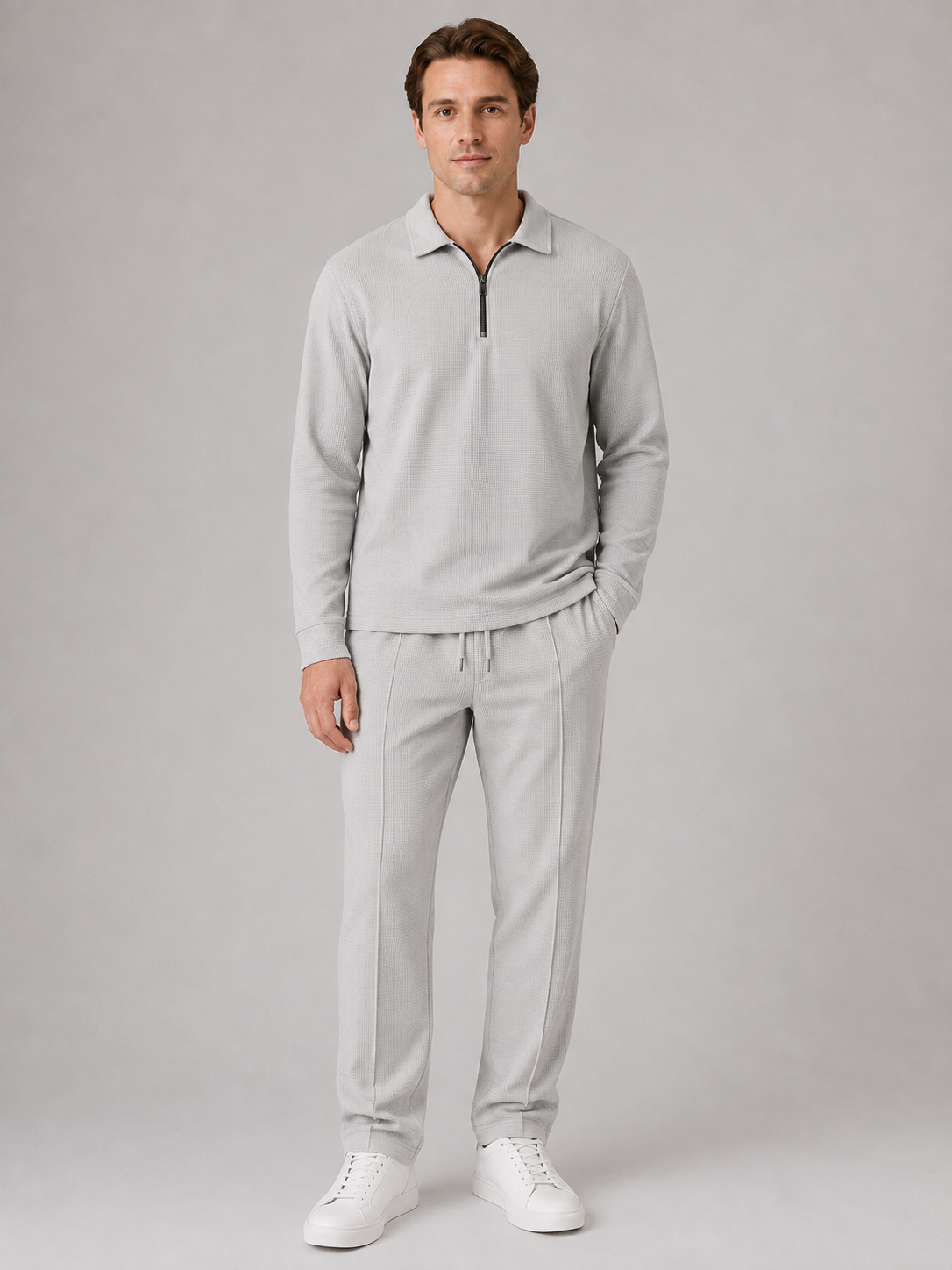 Man wearing light gray textured quarter-zip polo shirt and matching trousers with white sneakers
