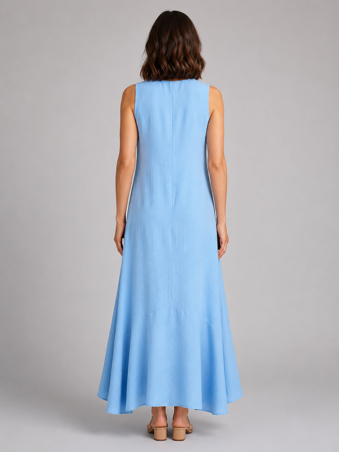 Woman wearing light blue sleeveless V-neck maxi dress with flowy silhouette, shown from back view