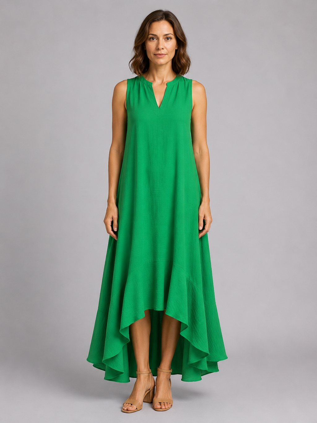 Woman wearing a sleeveless green v-neck maxi dress with asymmetrical high-low hem and flowing skirt