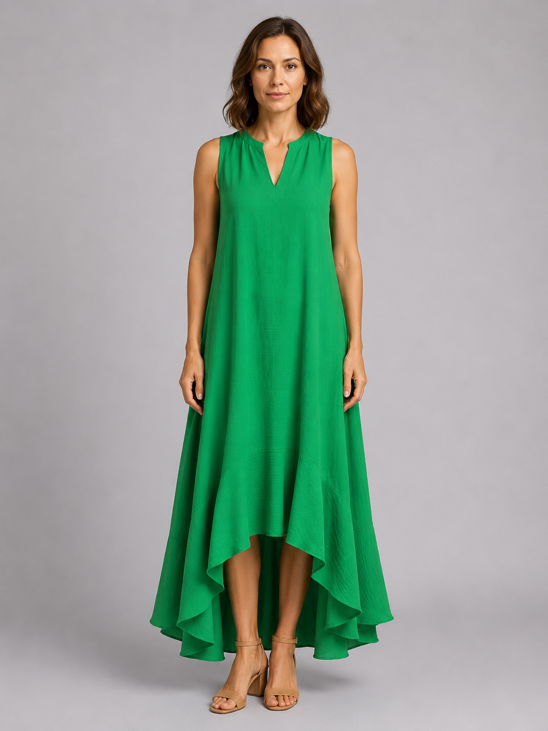 Woman wearing a sleeveless green v-neck maxi dress with asymmetrical high-low hem and flowing skirt
