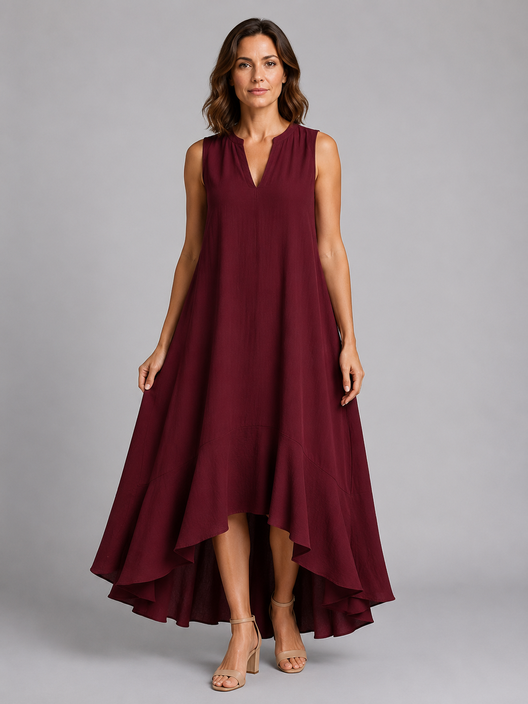 Woman wearing burgundy sleeveless V-neck maxi dress with asymmetrical high-low hem and tan sandals