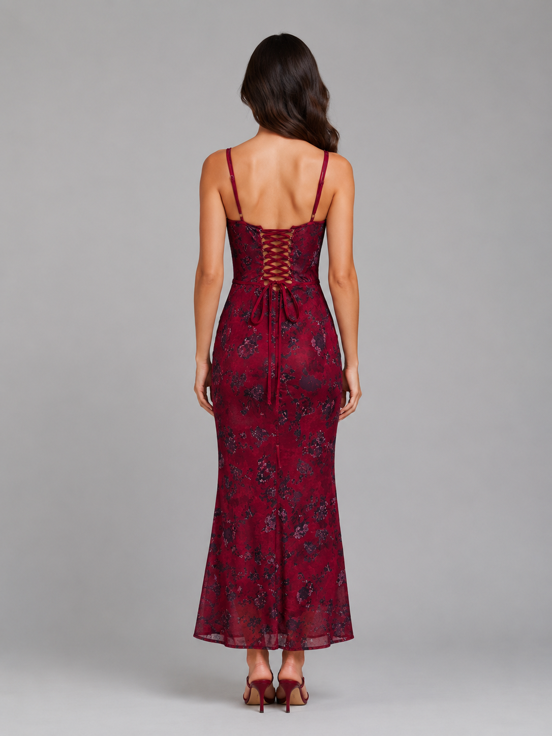 Woman wearing burgundy floral corset maxi dress with lace-up back detail and spaghetti straps, viewed from behind