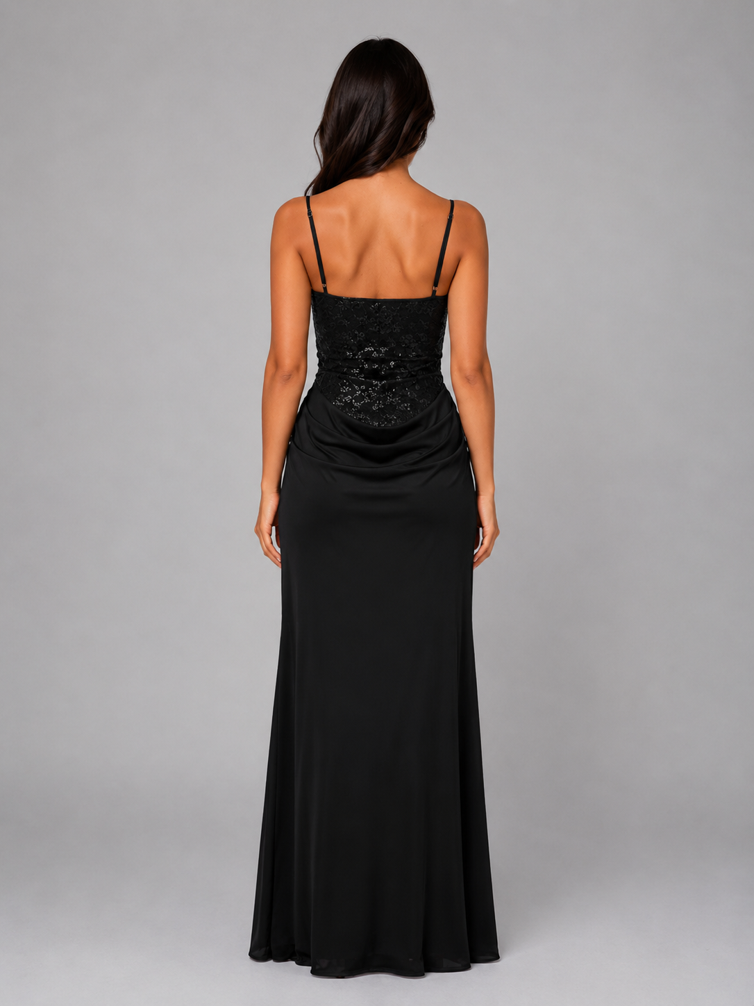 Woman wearing black Eloise evening maxi dress with lace bodice and ruched waist, viewed from behind against gray background