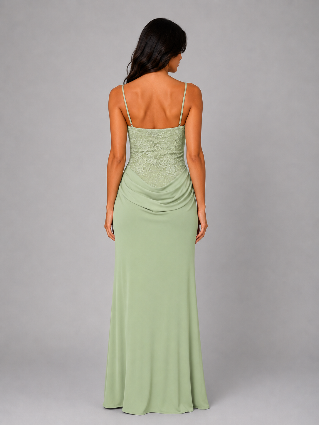 Woman wearing light green ruched evening maxi dress with lace bodice and thin straps, shown from back view