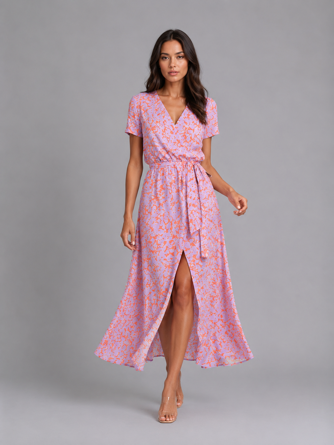 Woman wearing pink and coral floral print midi wrap dress with short sleeves, V-neckline, tie waist, and high slit