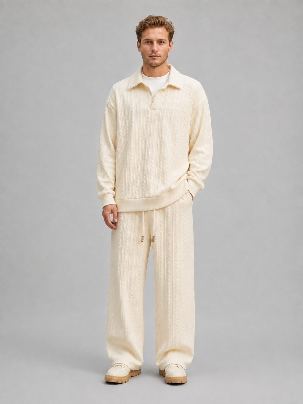Man wearing cream cable knit collared sweater and matching wide-leg trousers with drawstring waist and cream platform shoes