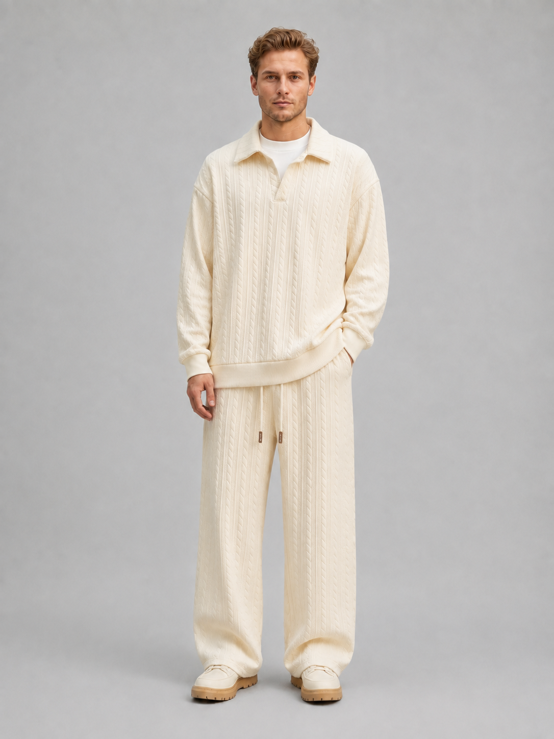 Man wearing cream cable knit collared sweater and matching wide-leg trousers with drawstring waist and cream platform shoes