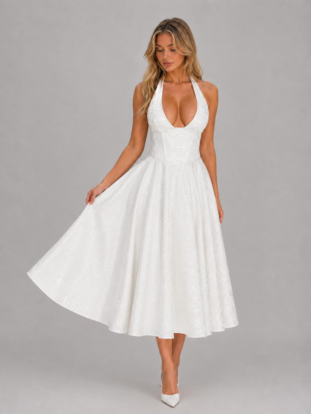 Woman wearing white halter Iris jacquard midi dress with full skirt, paired with white heels against gray background
