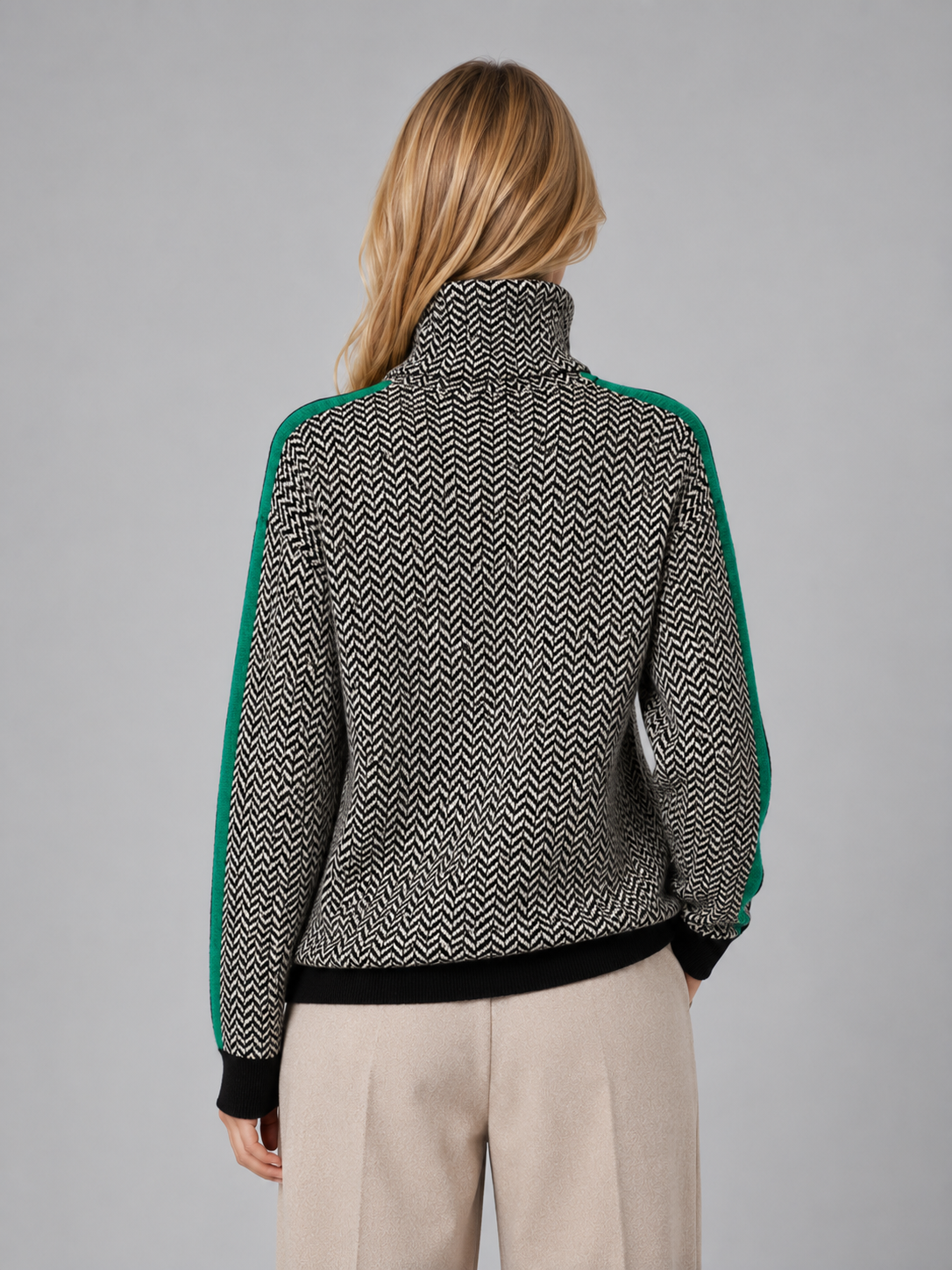 Woman wearing herringbone pattern turtleneck jumper with green sleeves and black ribbed cuffs, shown from behind