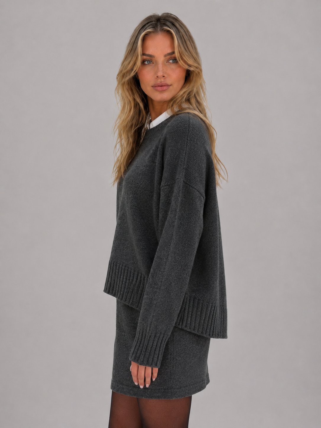 Woman wearing charcoal gray knitted jumper with white collar and matching mini skirt two-piece set, styled with dark tights
