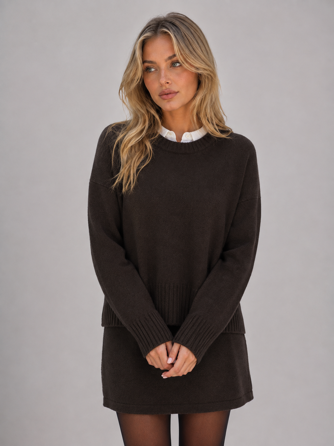 Woman wearing black knitted jumper with white collar and matching black mini skirt, styled with tights