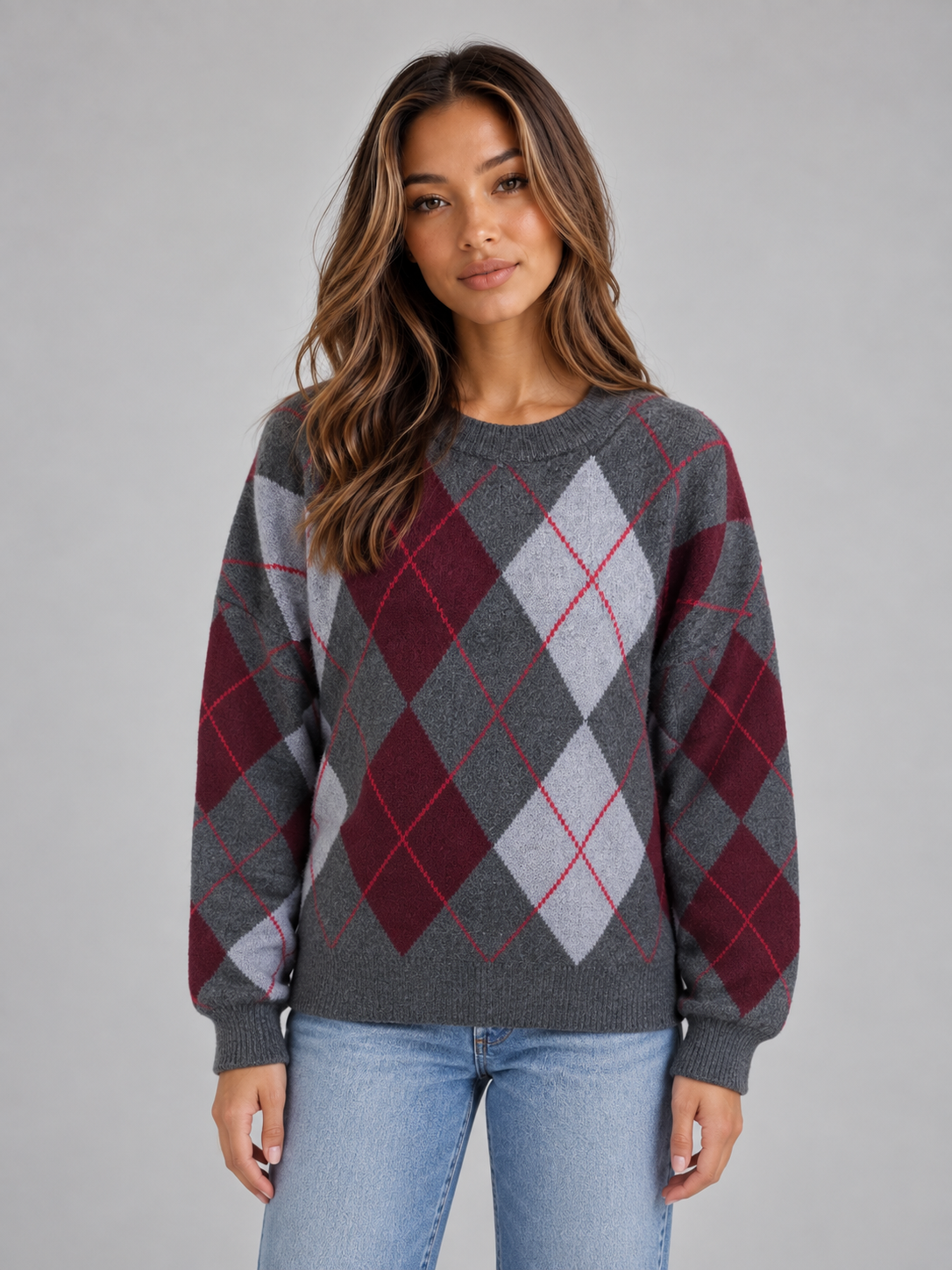 Woman wearing gray, burgundy and white argyle pattern crew neck knit sweater with long sleeves and light blue jeans