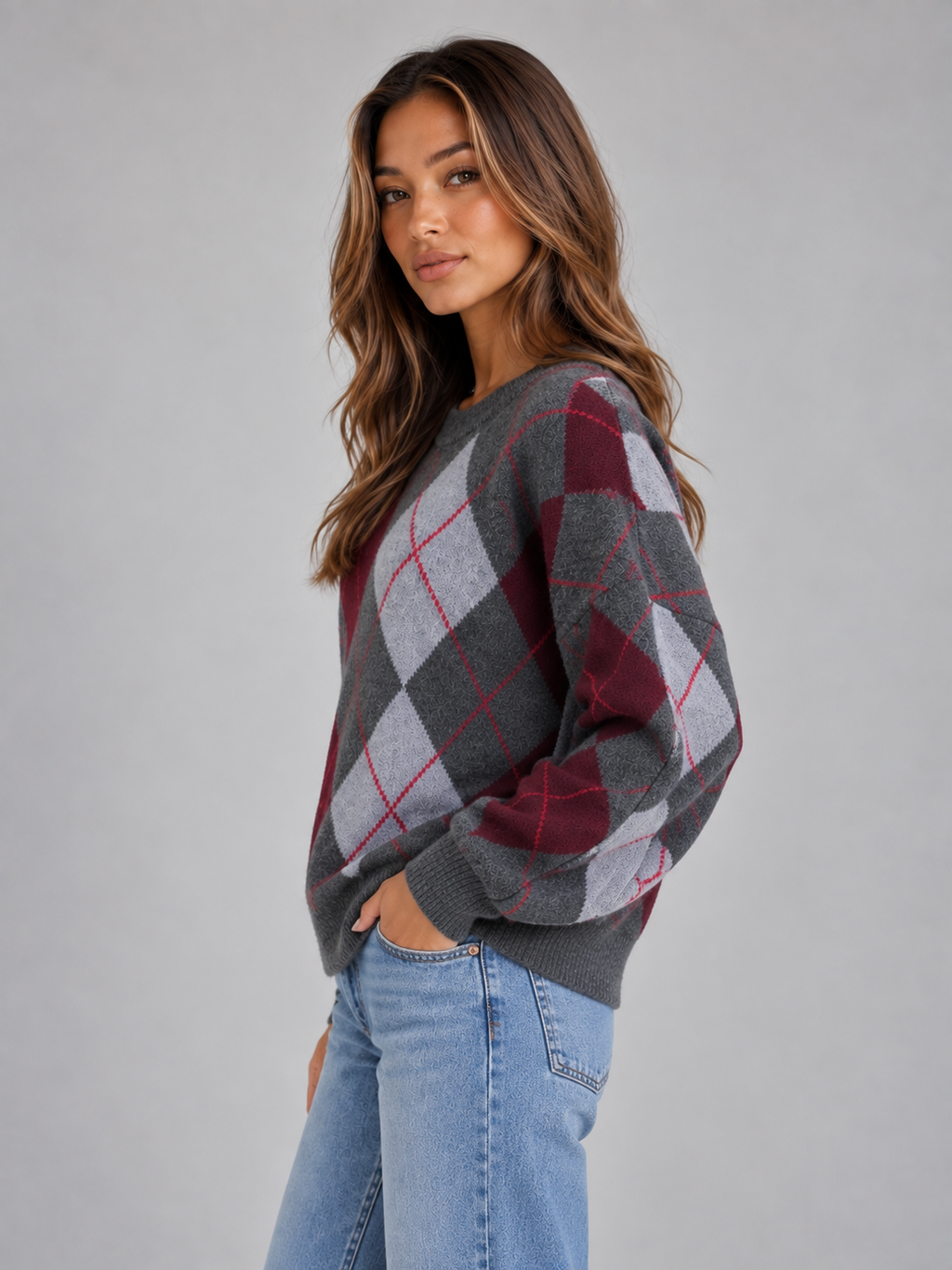 Woman wearing gray, burgundy and light blue argyle pattern crew neck knit sweater with long sleeves, styled with light blue jeans