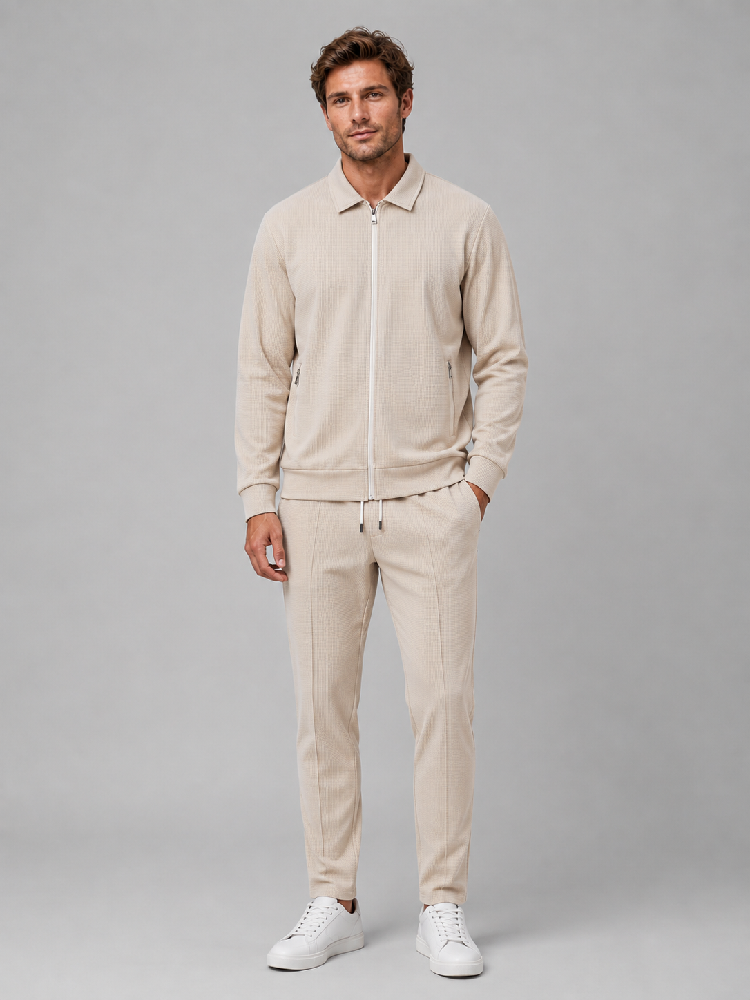 Man wearing cream textured zip jacket and matching tapered trousers with white sneakers