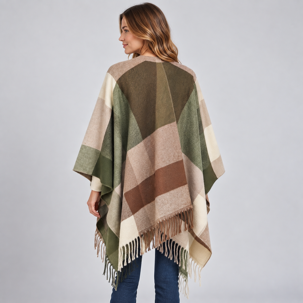 Woman wearing a colour block poncho blanket cape in olive, cream, tan and brown geometric pattern with fringe trim