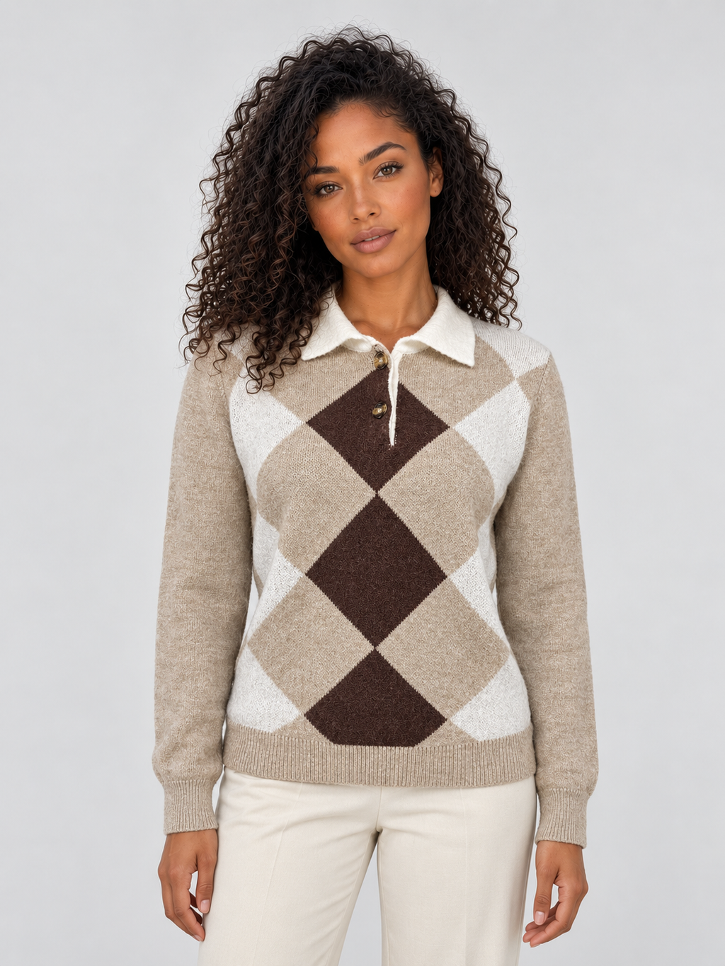 Woman wearing beige, white and brown argyle collared knit sweater with long sleeves and button neck detail, paired with cream pants