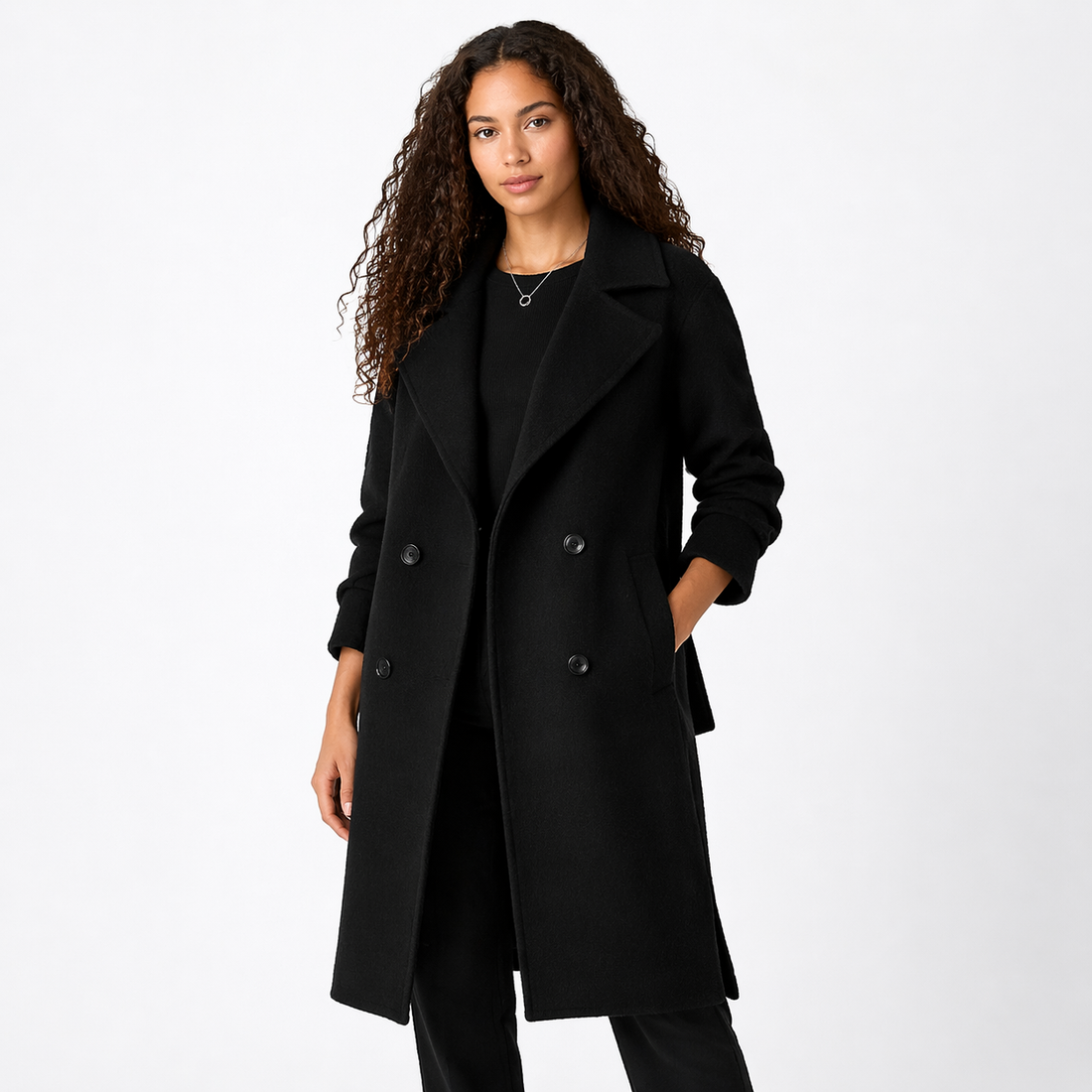 Woman wearing black double-breasted trench coat with belt, notch lapels, and long sleeves on white background