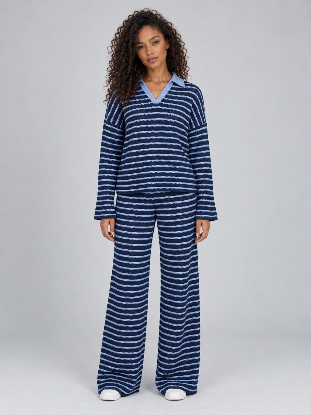 Woman wearing navy and light blue striped knit collared jumper with matching wide leg trousers and white sneakers