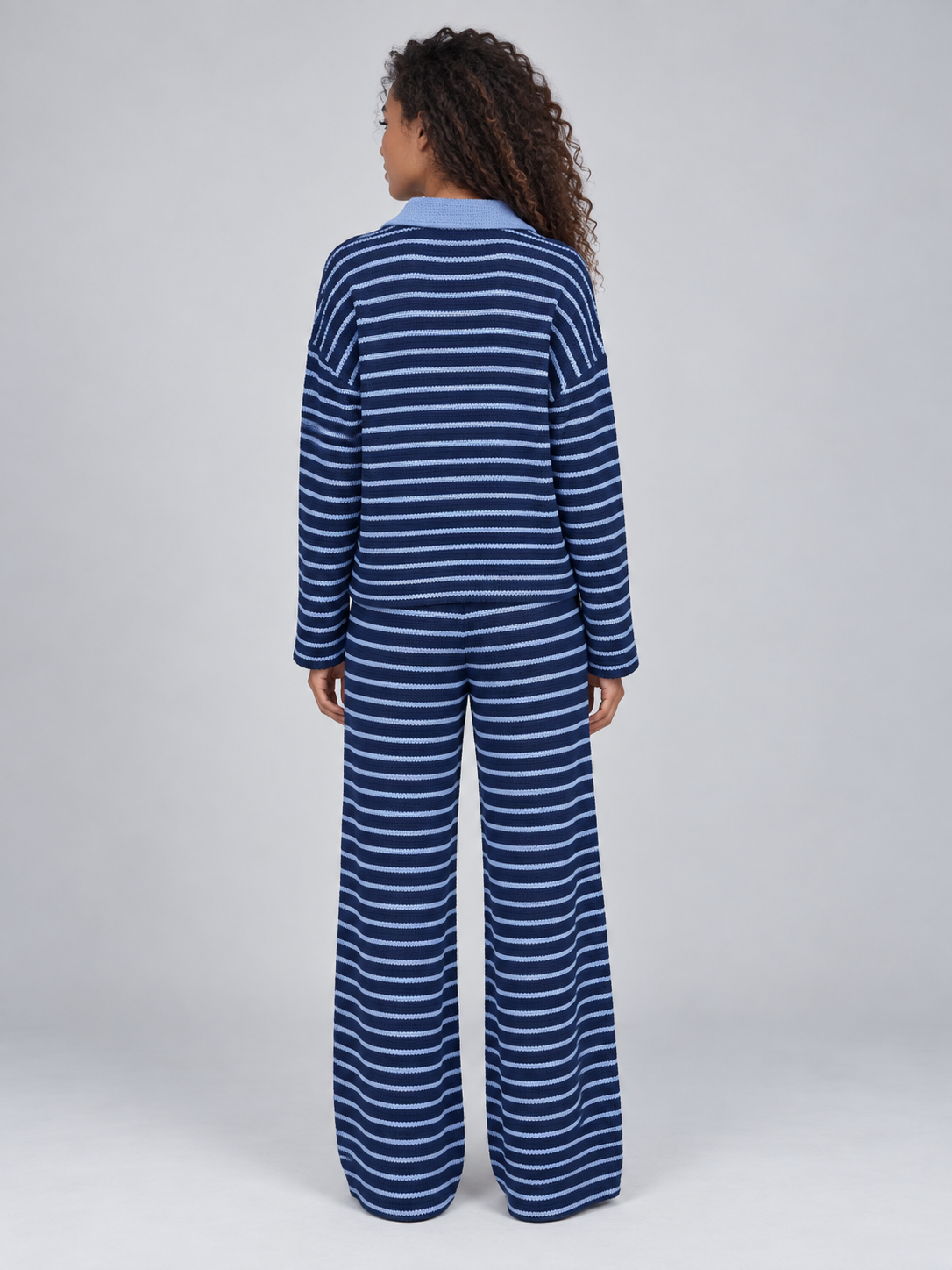 Woman wearing navy and light blue striped knit collared jumper and matching wide leg trousers, back view