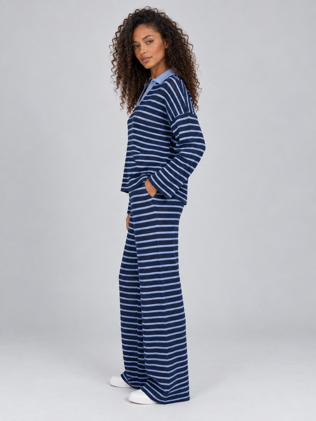 Woman wearing navy and light blue striped knit collared jumper with matching wide leg trousers and white sneakers