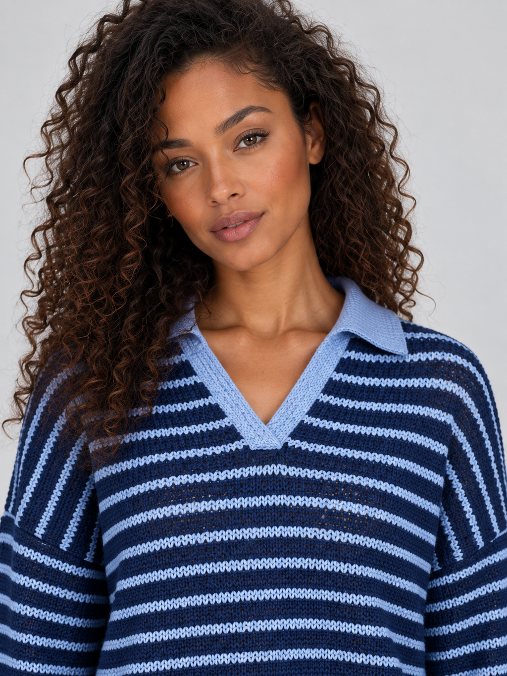 Woman wearing navy and light blue striped knit collared jumper with V-neckline