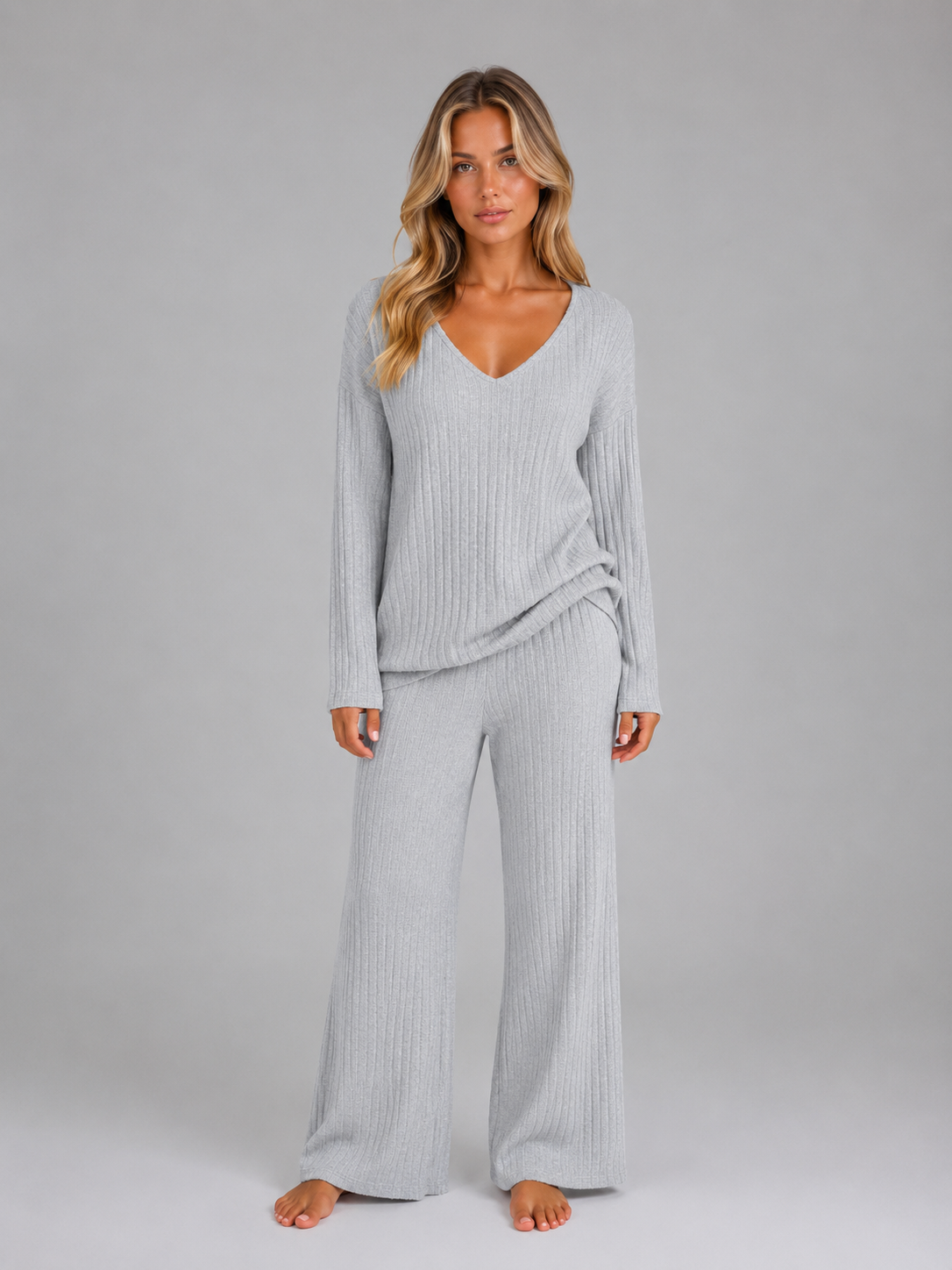 Woman wearing light gray ribbed knit v-neck long sleeve jumper and matching wide leg trousers lounge set