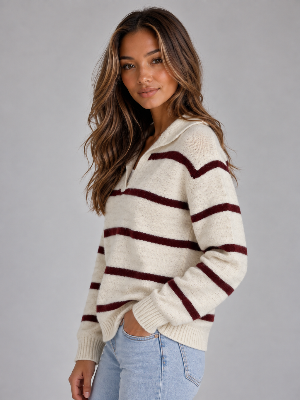 Woman wearing cream and burgundy striped v-neck wool knit sweater with long sleeves and light blue jeans