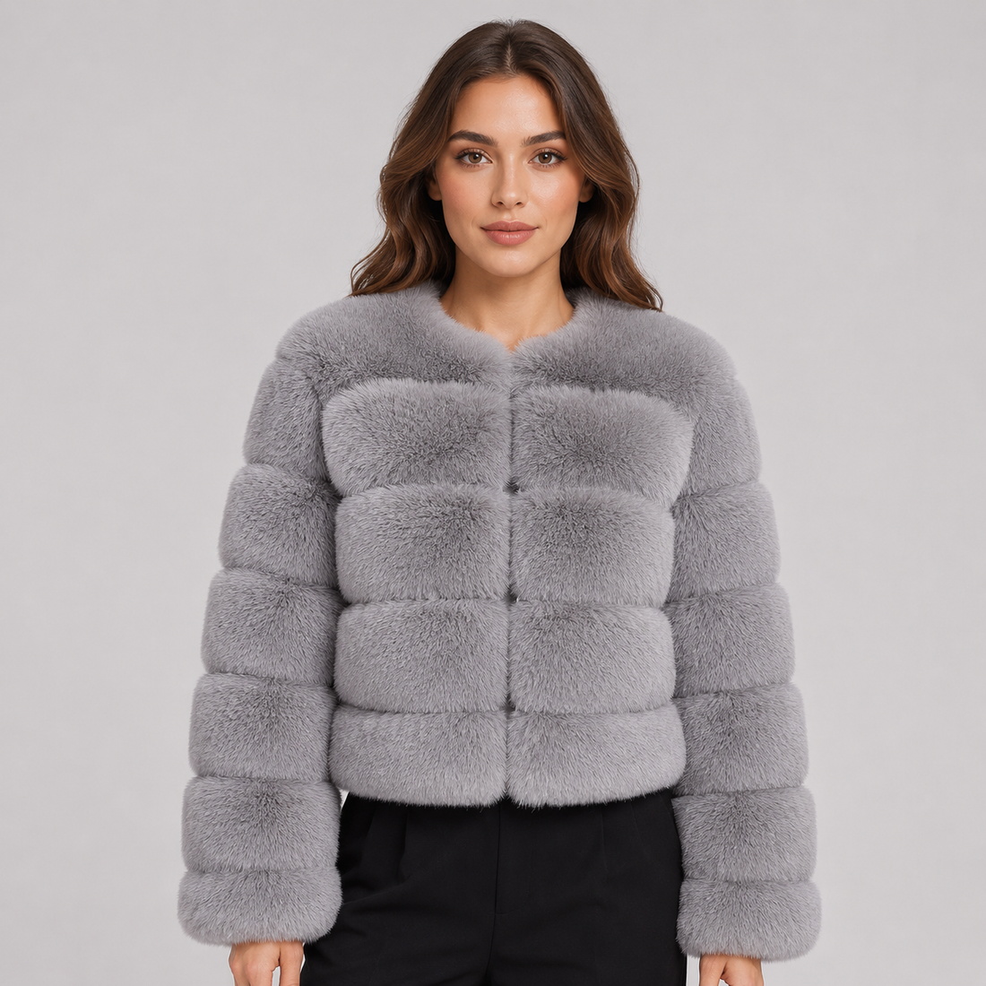 Woman wearing a gray cropped fluffy faux fur jacket with puffy quilted sections and black pants against a neutral background