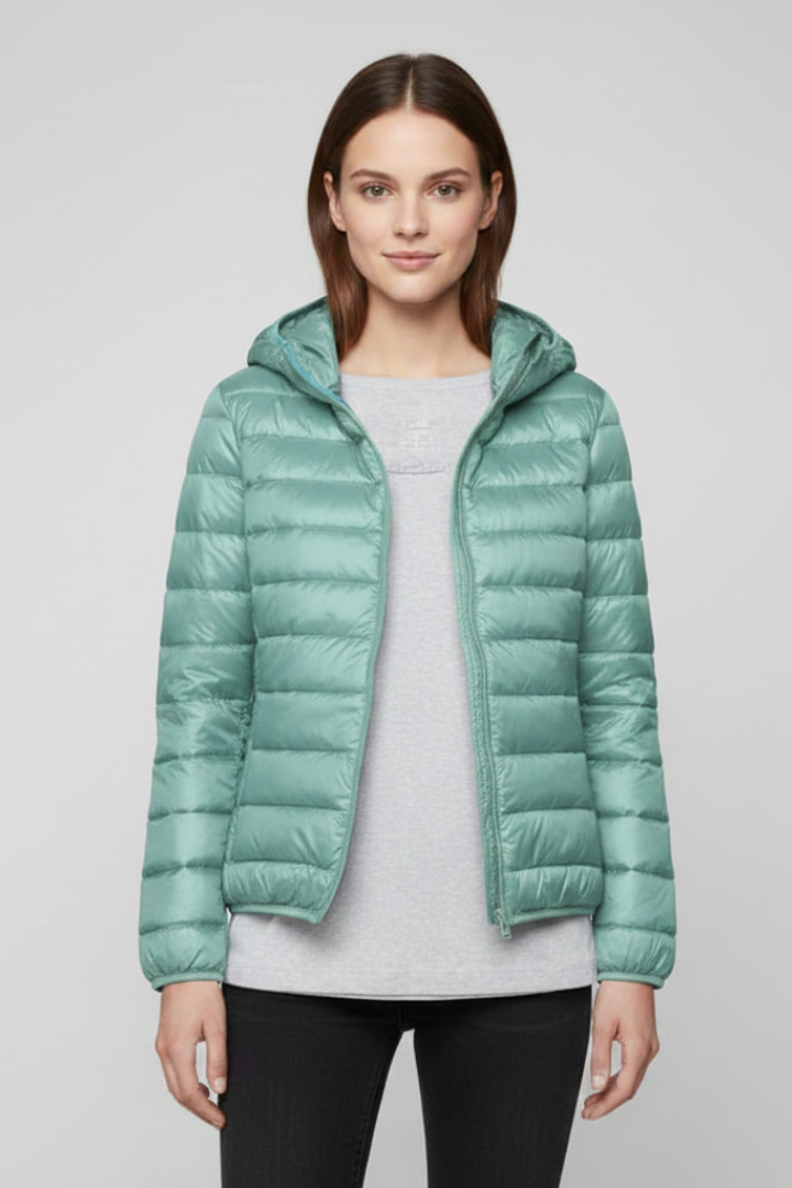 Woman wearing mint green quilted hooded puffer jacket with zip fastening over light gray shirt and black pants