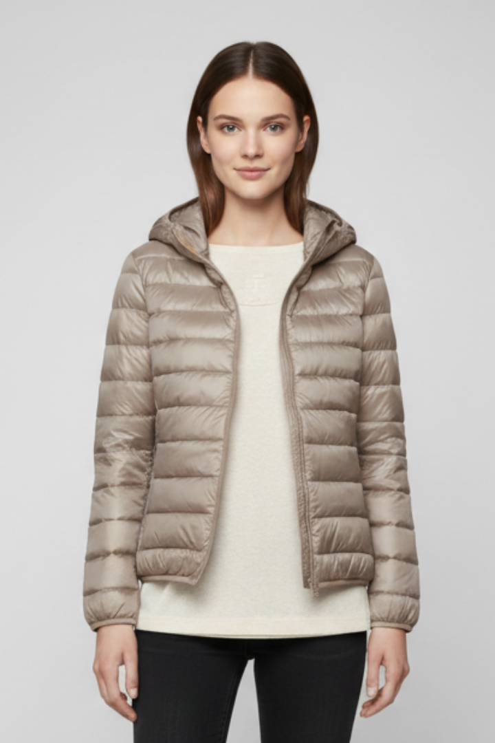 Woman wearing beige quilted hooded zip jacket over cream sweater with black pants, front view