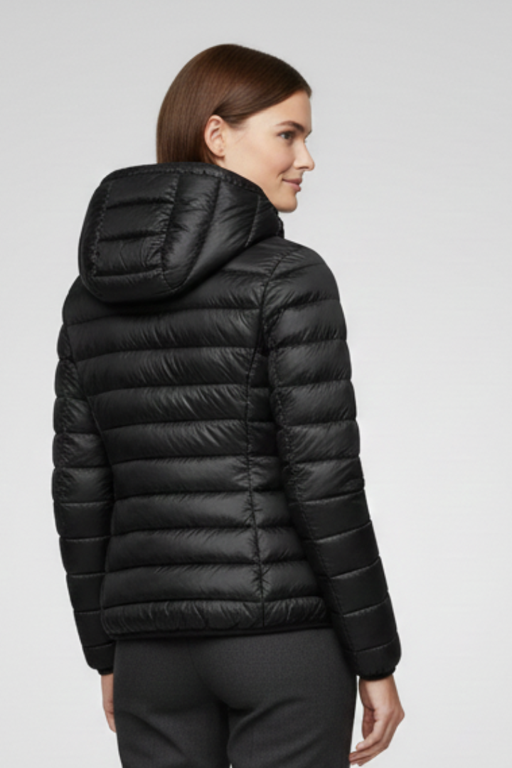 Woman wearing black quilted hooded zip-up jacket with horizontal stitching, shown from the back in profile view against neutral background