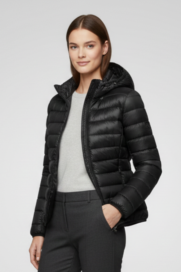 Woman wearing black quilted hooded puffer jacket with zip fastening over gray top and dark pants