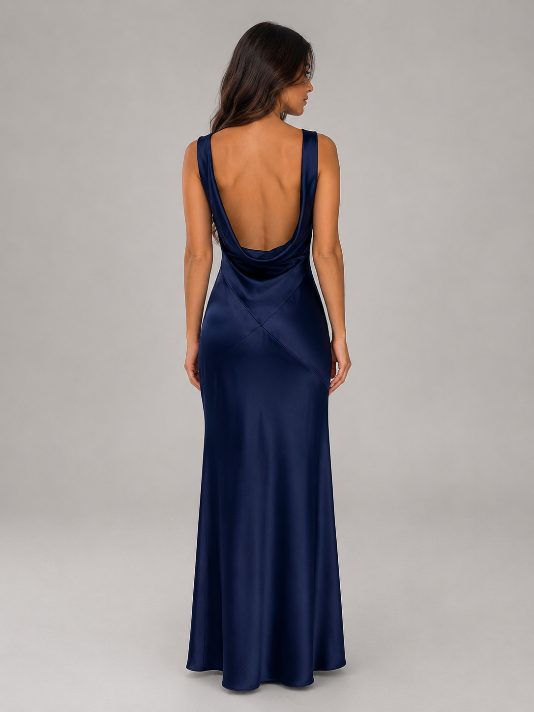 Woman wearing navy satin open back sleeveless maxi dress with cowl back detail, viewed from behind