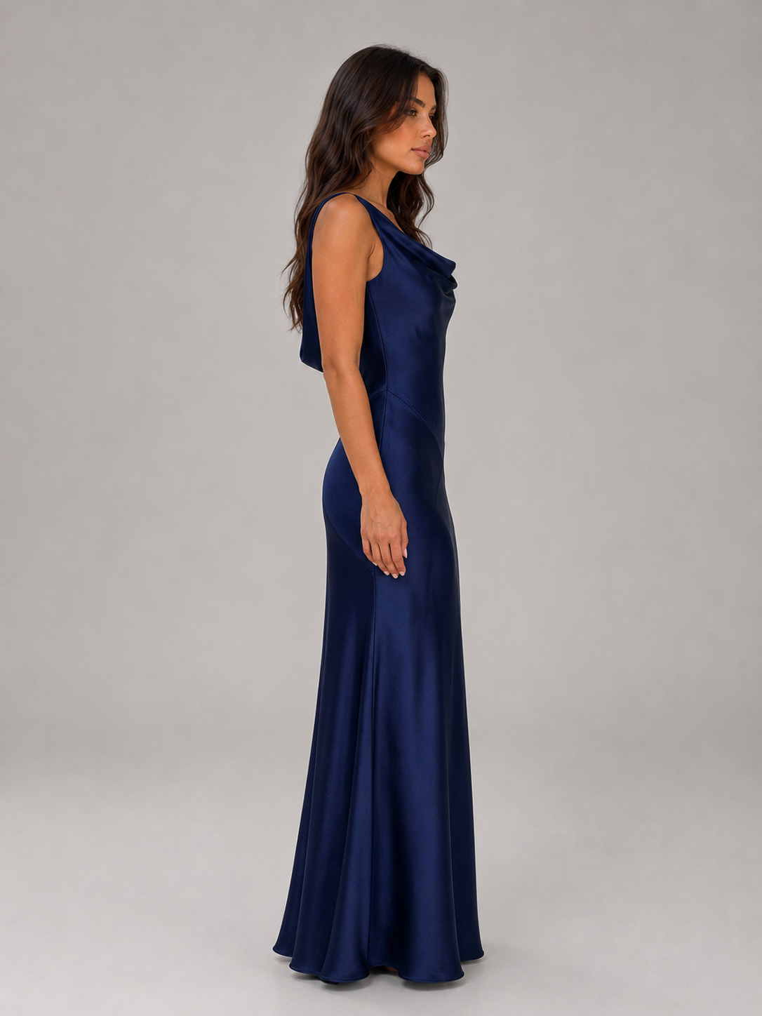 Woman wearing indigo open back satin evening maxi dress with cowl neckline, side view